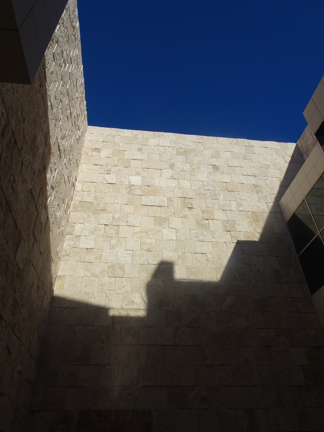 A travertine wall with brilliant sun and dark shadows, the Fountain Alcove.